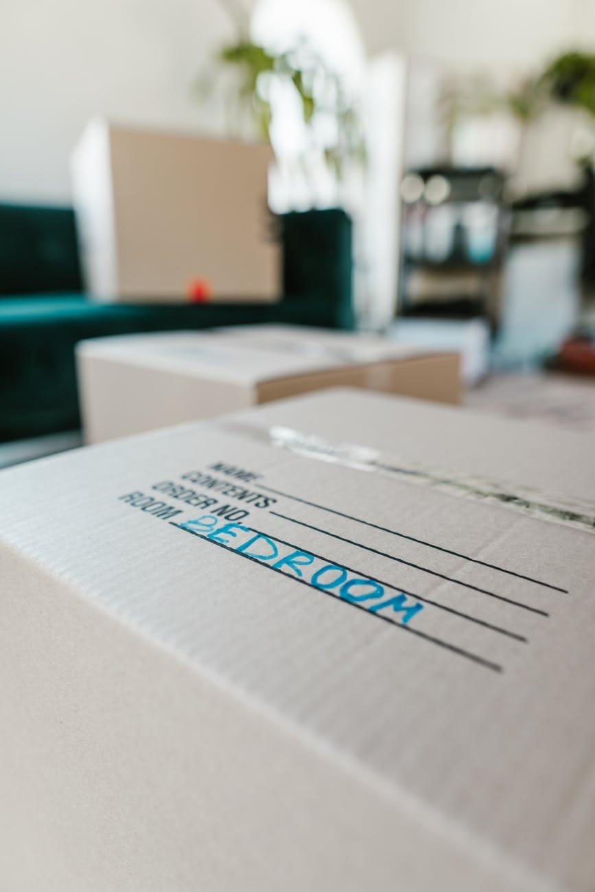 Cardboard moving boxes, one clearly marked BEDROOM, ready for relocation