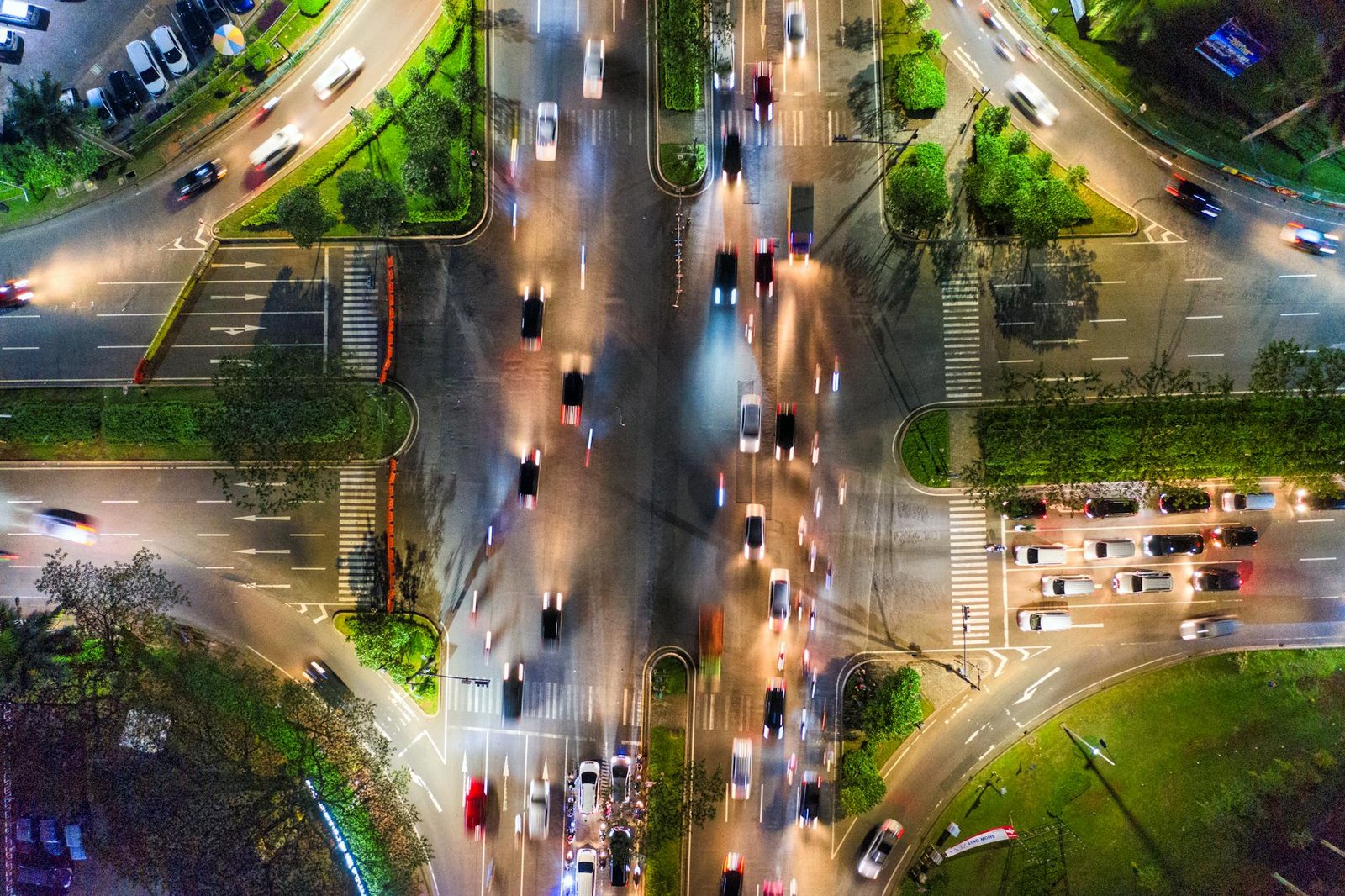 Overhead view of a busy city intersection at night with car light trails