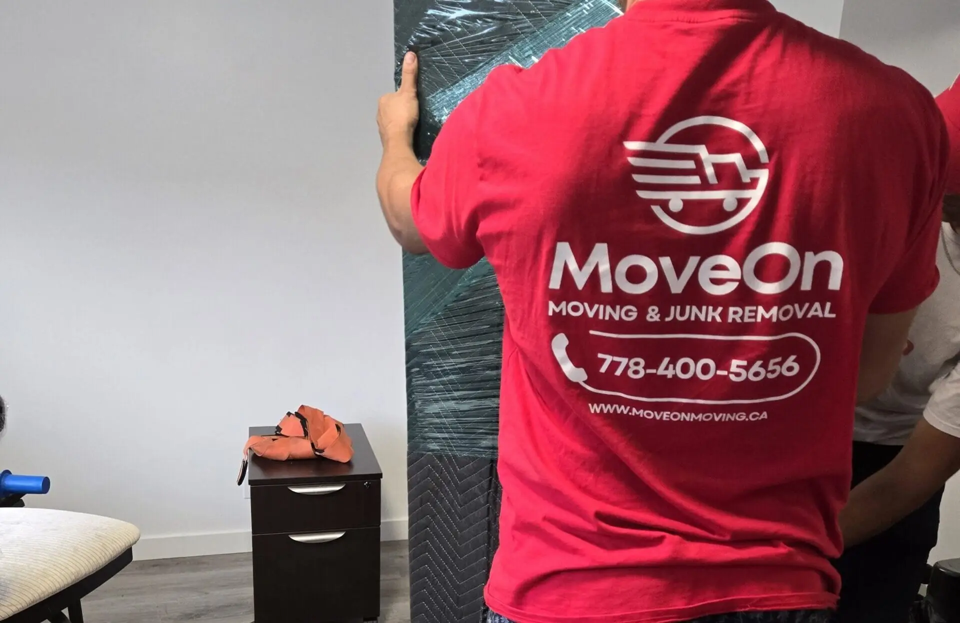 MoveOn crew member carrying a wrapped mattress out to the truck